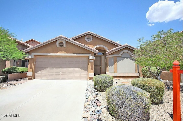 view of front facade featuring a tiled roof, stucco siding, an attached garage, and concrete driveway