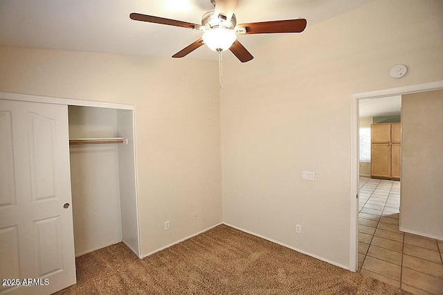 unfurnished bedroom with a closet, ceiling fan, carpet flooring, and tile patterned flooring