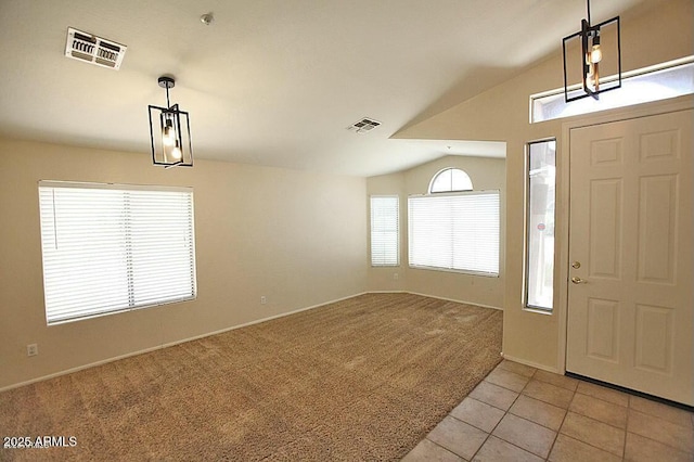 foyer entrance with light tile patterned floors, visible vents, light colored carpet, and vaulted ceiling