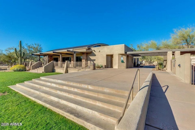 back of property featuring a carport, stucco siding, driveway, and a lawn