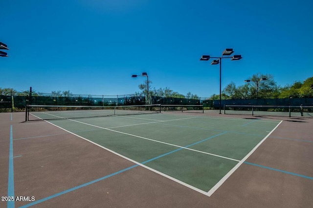 view of tennis court with community basketball court and fence