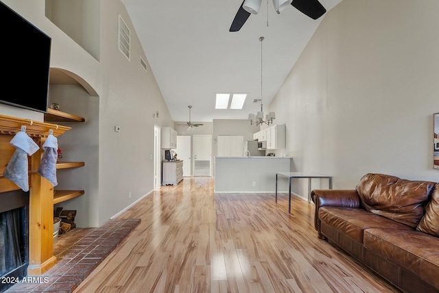 living room with ceiling fan with notable chandelier, light wood-type flooring, and high vaulted ceiling