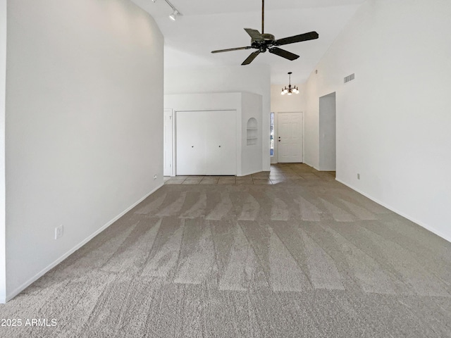 unfurnished living room with rail lighting, ceiling fan with notable chandelier, light carpet, and high vaulted ceiling