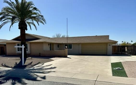 ranch-style house featuring concrete driveway, fence, and an attached garage