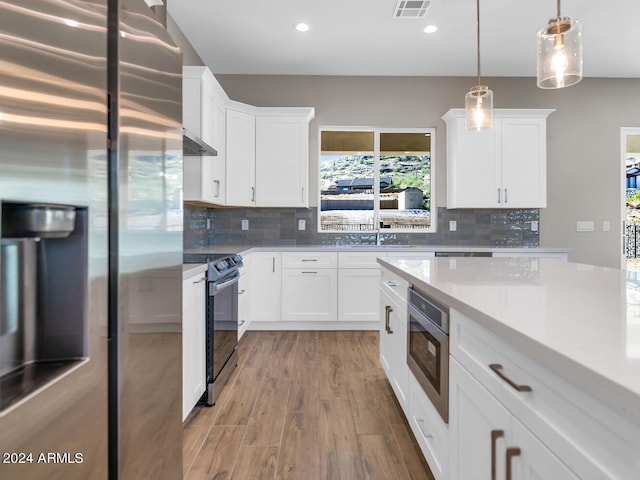 kitchen with hardwood / wood-style floors, white cabinetry, stainless steel appliances, and backsplash