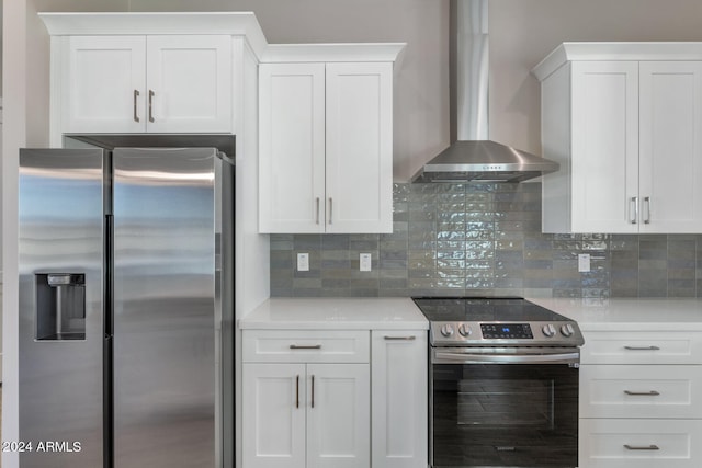 kitchen with wall chimney exhaust hood, white cabinetry, and stainless steel appliances