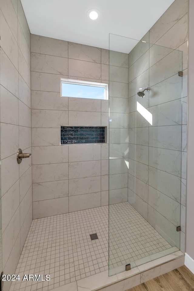 bathroom with wood-type flooring and tiled shower