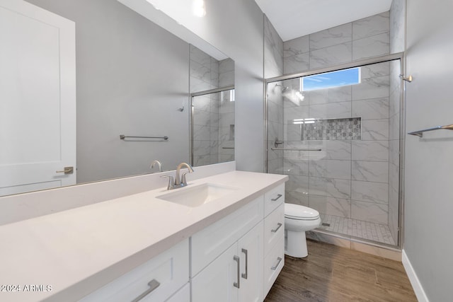 bathroom featuring a shower with door, vanity, wood-type flooring, and toilet