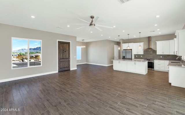 kitchen with white cabinets, stainless steel appliances, dark wood-type flooring, wall chimney exhaust hood, and a center island