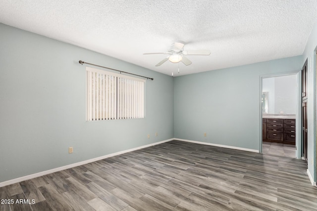 12811 N 44th Dr, Glendale, AZ 85304 - unfurnished bedroom with wood finished floors, a textured ceiling, baseboards, connected bathroom, and ceiling fan