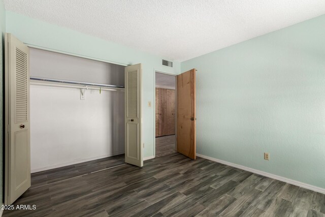 12811 N 44th Dr, Glendale, AZ 85304 - unfurnished bedroom featuring dark wood-style floors, a closet, baseboards, and a textured ceiling