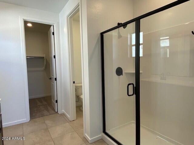 bathroom featuring toilet, tile patterned floors, and a shower with shower door