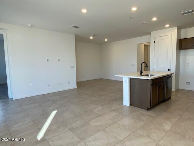 kitchen with dark brown cabinets, dishwasher, sink, and a center island with sink