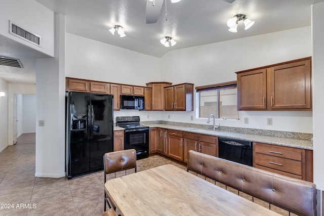 kitchen with black appliances, light tile patterned floors, high vaulted ceiling, light stone countertops, and sink