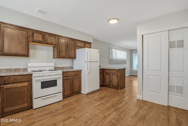 kitchen featuring light wood-type flooring, white appliances, visible vents, and light countertops