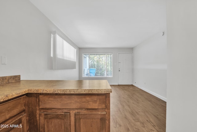 kitchen with light countertops, a peninsula, baseboards, and wood finished floors