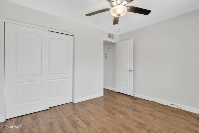 unfurnished bedroom with a closet, visible vents, ceiling fan, wood finished floors, and baseboards