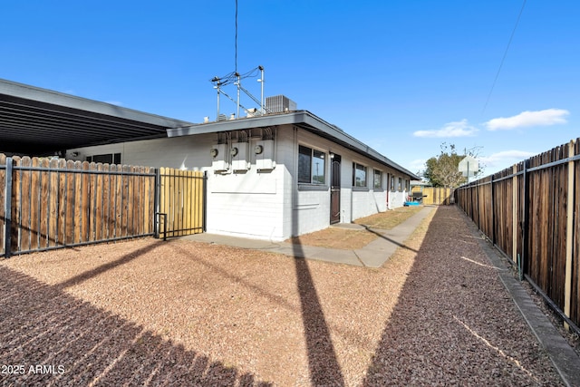 view of property exterior featuring fence private yard, concrete block siding, and central air condition unit