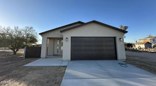 single story home with a garage, driveway, and stucco siding