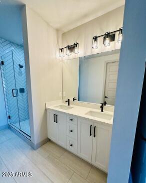 bathroom with baseboards, double vanity, a sink, and a shower stall