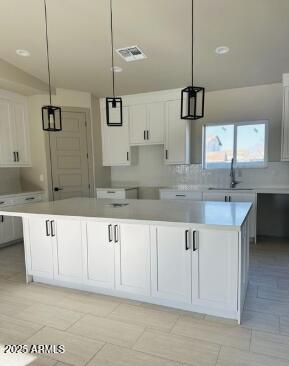 kitchen featuring pendant lighting, visible vents, a sink, and white cabinetry