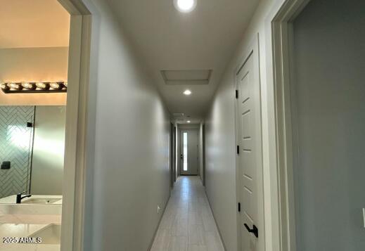 corridor with recessed lighting, light wood-style flooring, and attic access