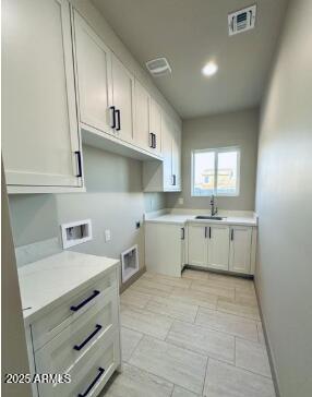 washroom with cabinet space, baseboards, visible vents, hookup for a washing machine, and a sink