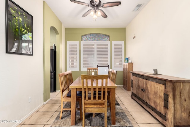 dining space featuring light tile patterned flooring, arched walkways, a ceiling fan, baseboards, and visible vents