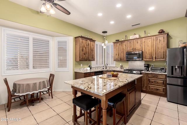 kitchen featuring appliances with stainless steel finishes, light tile patterned floors, visible vents, and a center island