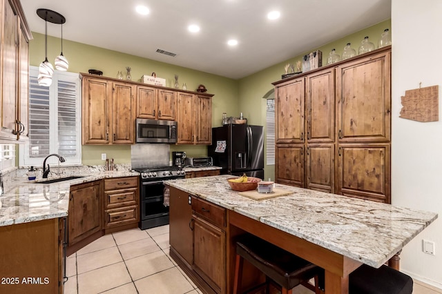 kitchen featuring light stone countertops, appliances with stainless steel finishes, a breakfast bar, a sink, and visible vents
