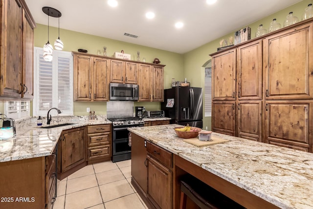 kitchen with visible vents, pendant lighting, light stone countertops, a sink, and stainless steel appliances