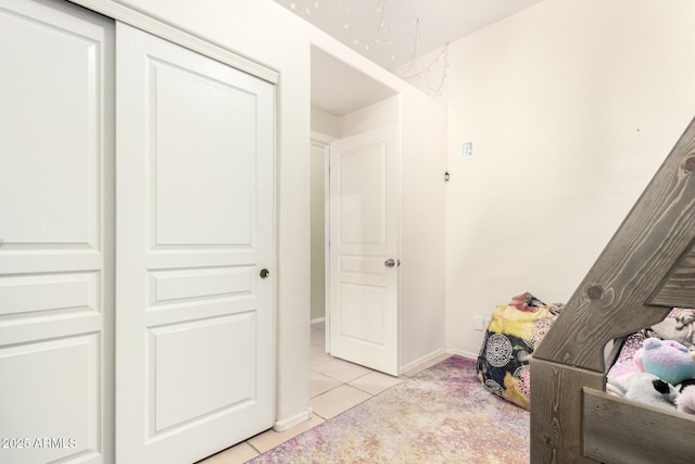 bedroom featuring baseboards, light tile patterned floors, and a closet