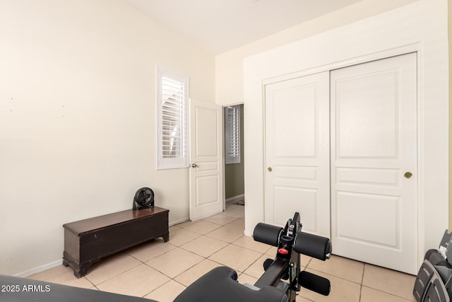 exercise room with baseboards and light tile patterned flooring