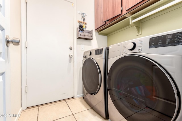 washroom with light tile patterned floors, washing machine and dryer, and cabinet space