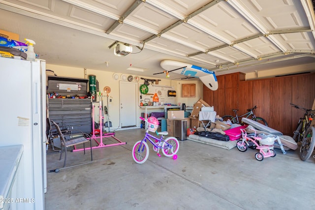 garage featuring freestanding refrigerator, wooden walls, and a garage door opener