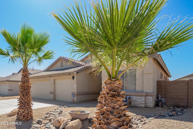 view of front of property with concrete driveway, an attached garage, fence, and stucco siding