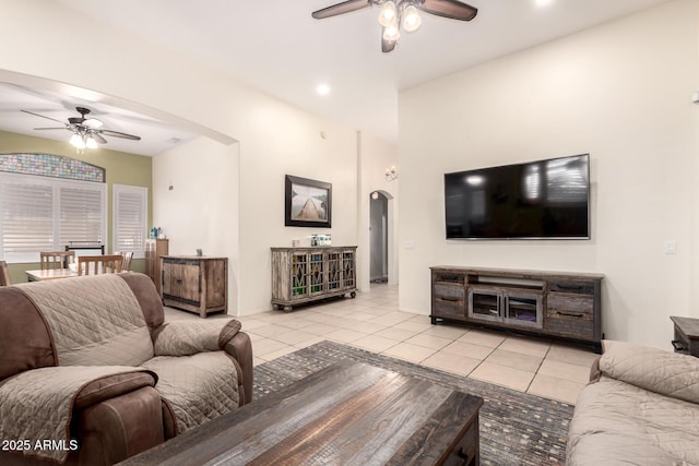 living area with baseboards, arched walkways, ceiling fan, and light tile patterned floors