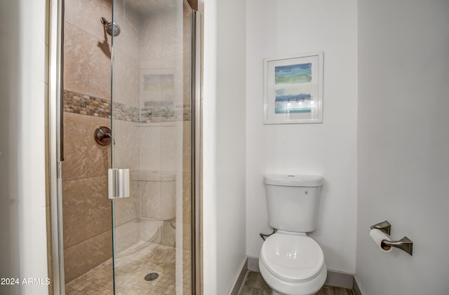 bathroom featuring a shower with door and toilet