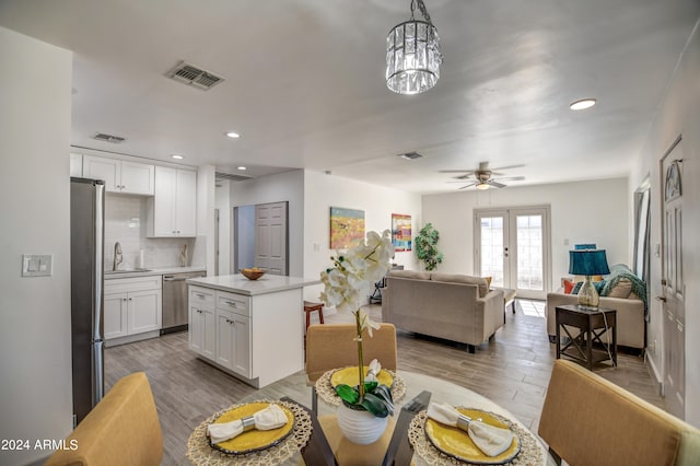 dining room featuring sink, french doors, ceiling fan with notable chandelier, and light wood-type flooring