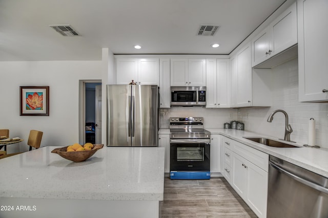 kitchen featuring light stone countertops, sink, light wood-type flooring, white cabinetry, and stainless steel appliances