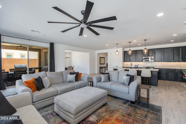 living room featuring ceiling fan, sink, and hardwood / wood-style floors