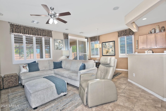 living area featuring light tile patterned floors, a ceiling fan, visible vents, and baseboards