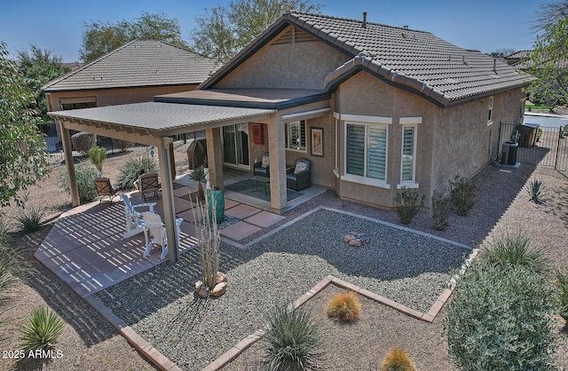 rear view of property with a patio, central AC unit, a tile roof, fence, and stucco siding