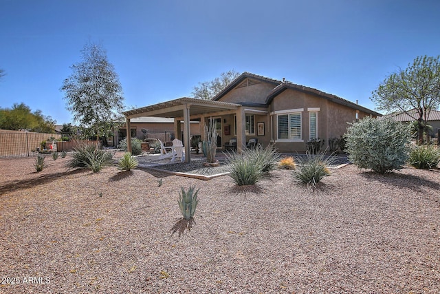 back of property with stucco siding, fence, and a patio