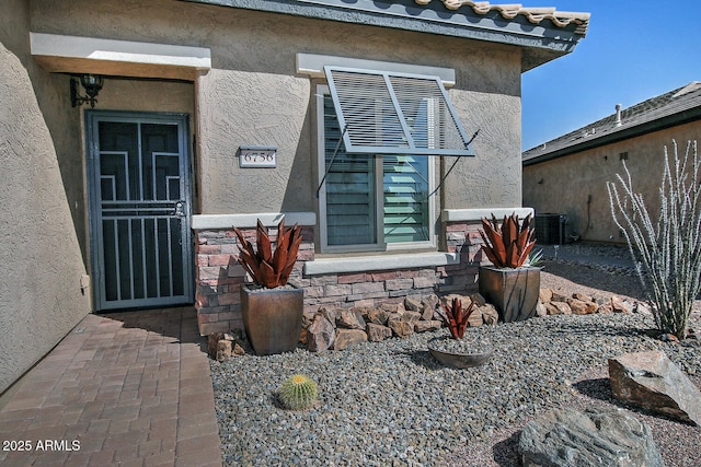 entrance to property with central AC unit and stucco siding