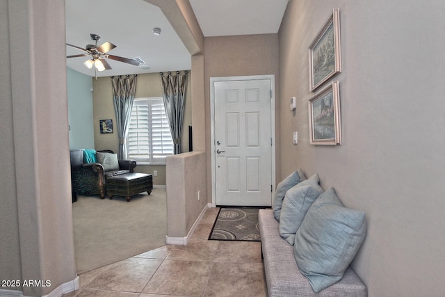 entrance foyer featuring carpet, ceiling fan, baseboards, and tile patterned flooring