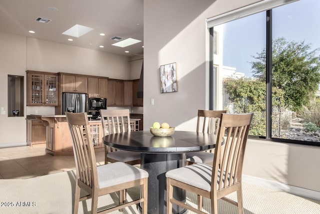 tiled dining space featuring a skylight and a high ceiling