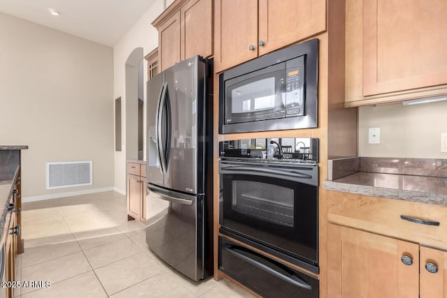 kitchen featuring built in microwave, stainless steel fridge with ice dispenser, light tile patterned floors, and black oven