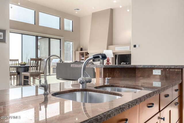 kitchen with a high ceiling, sink, and dark stone countertops