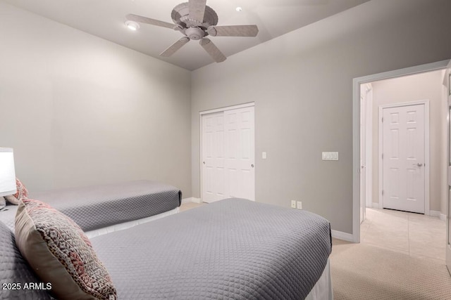 bedroom featuring light colored carpet, ceiling fan, and a closet